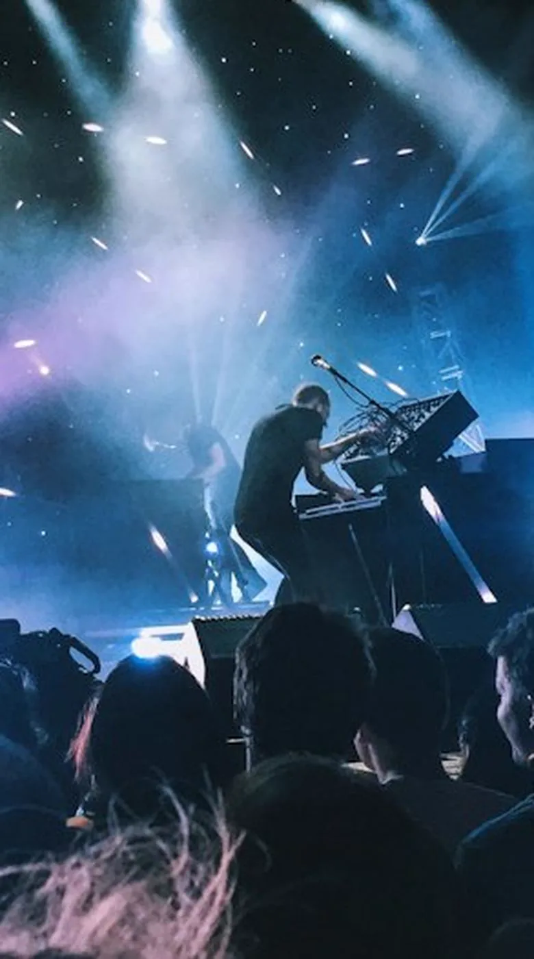 Band on stage under blue light, shot from the crowd